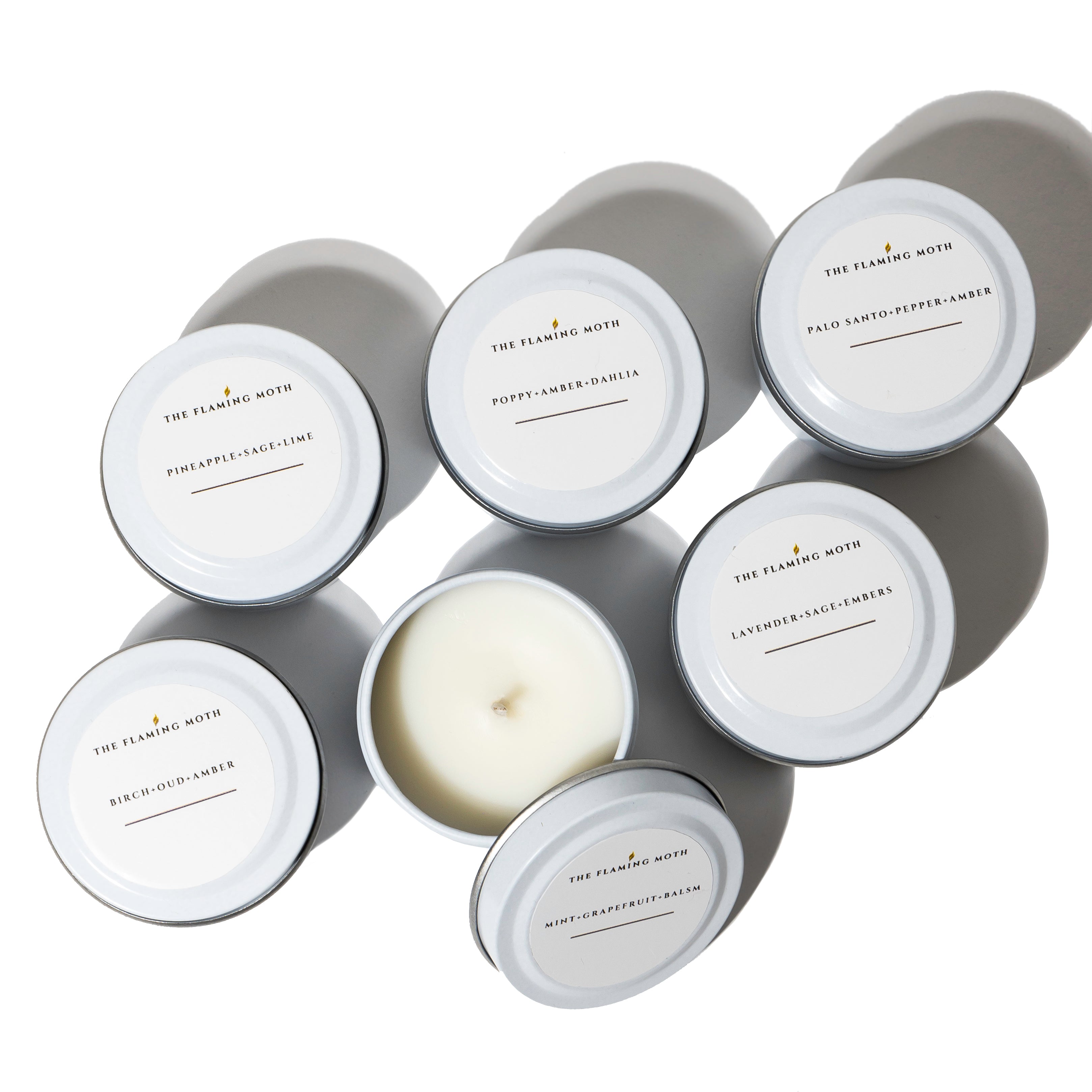 Set of candles in gray tins with white lids on a white background