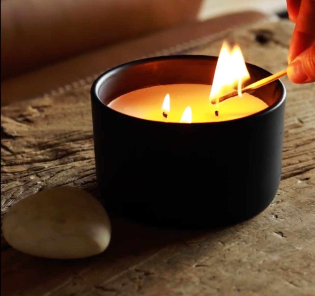 Candle being lit with a match on a rustic wooden surface