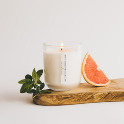 mint grapefruit balsam candle with grapefruit slice and mint leaves on wood board
