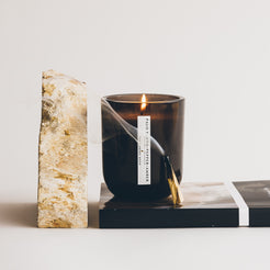 palo santo pepper amber candle with burning palo santo next to rock