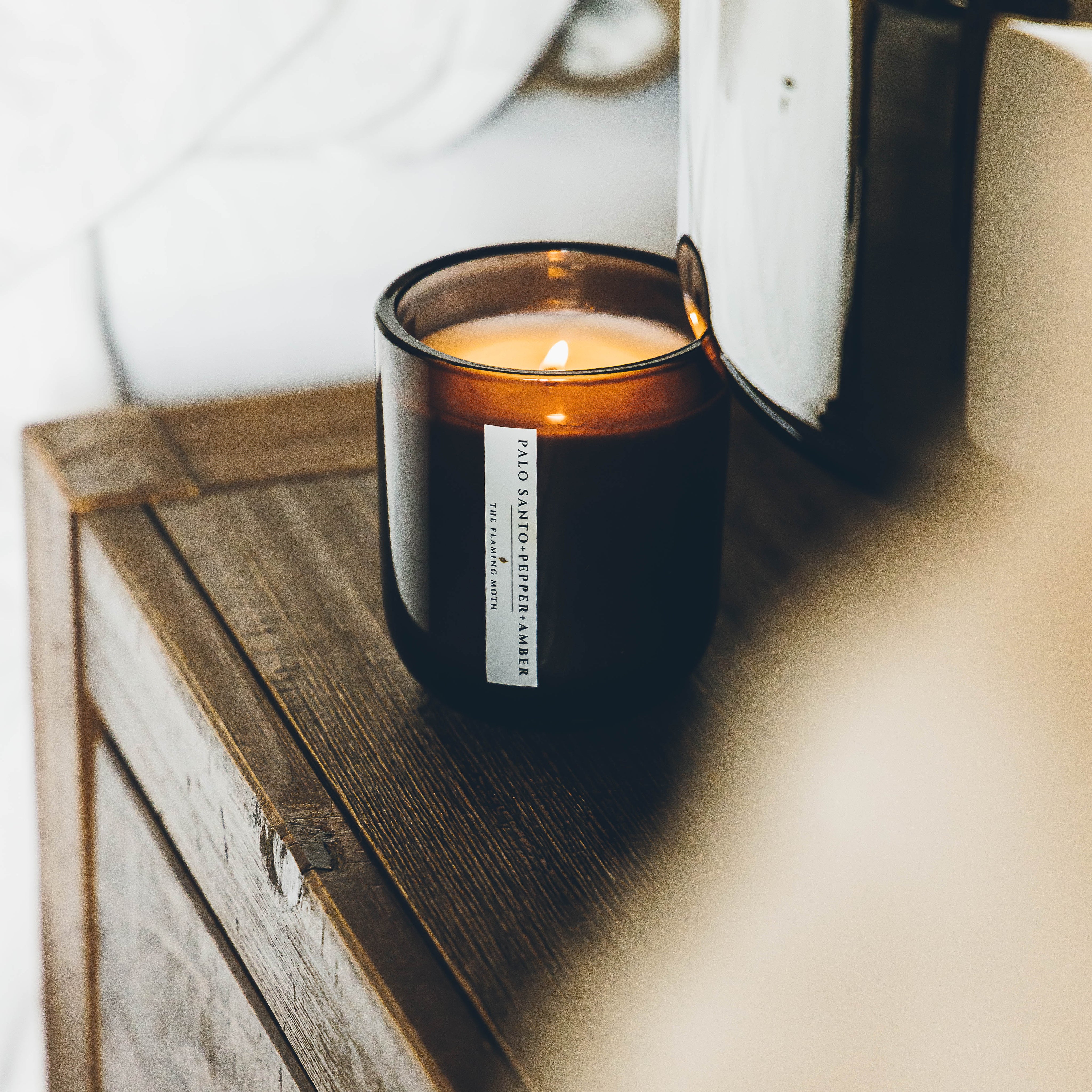 palo santo pepper amber candle on dark wood nightstand