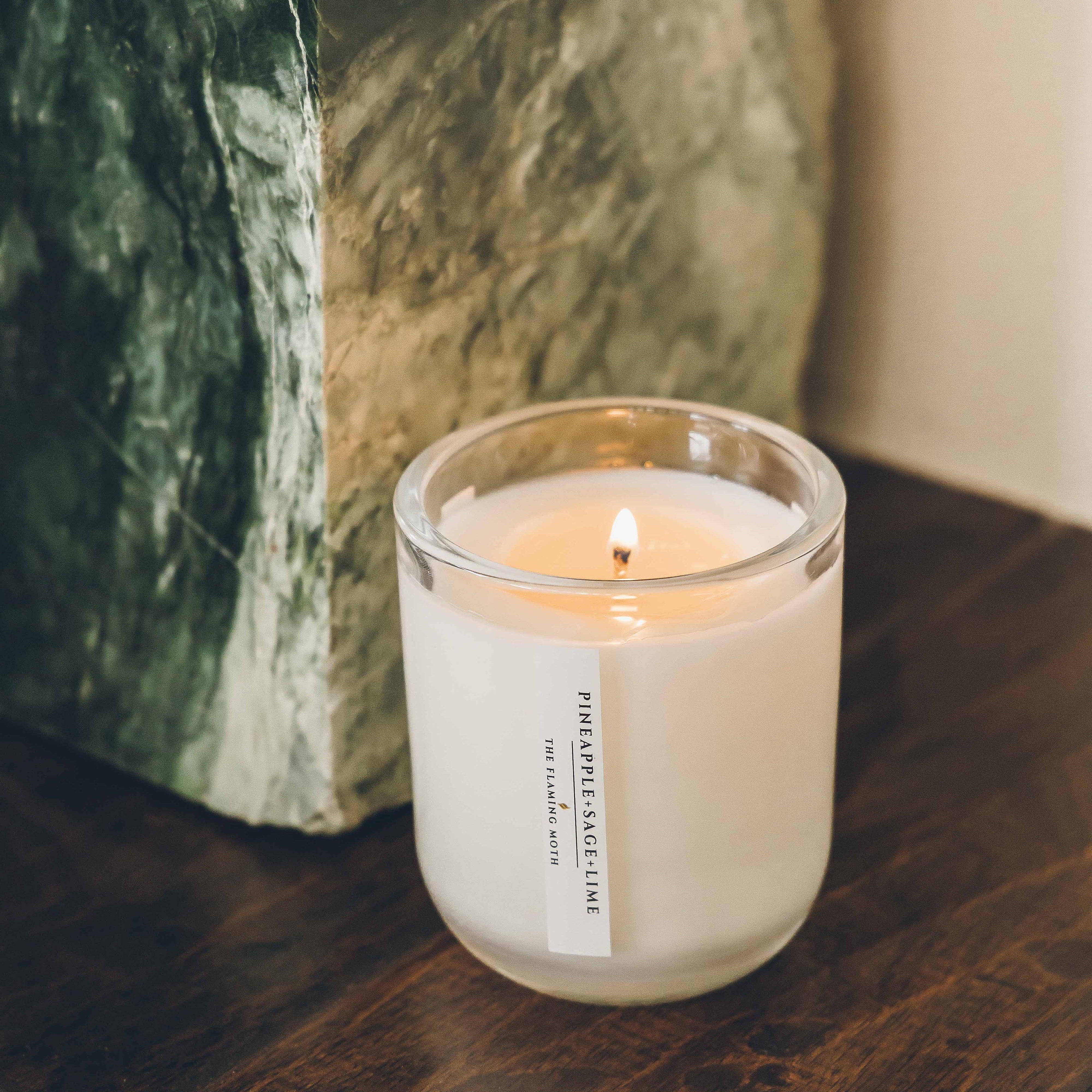 pineapple sage lime candle on table next to stone sculpture