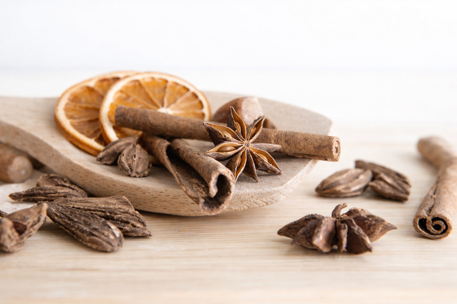 Spices including cinnamon sticks, star anise, and orange slices on a wooden surface.